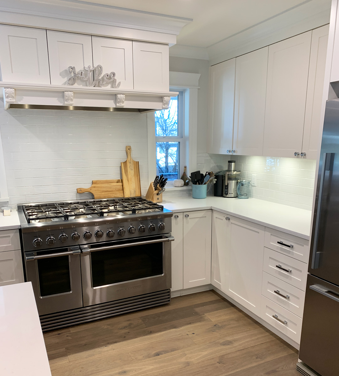 All-white farmhouse style kitchen with stainless steel appliances