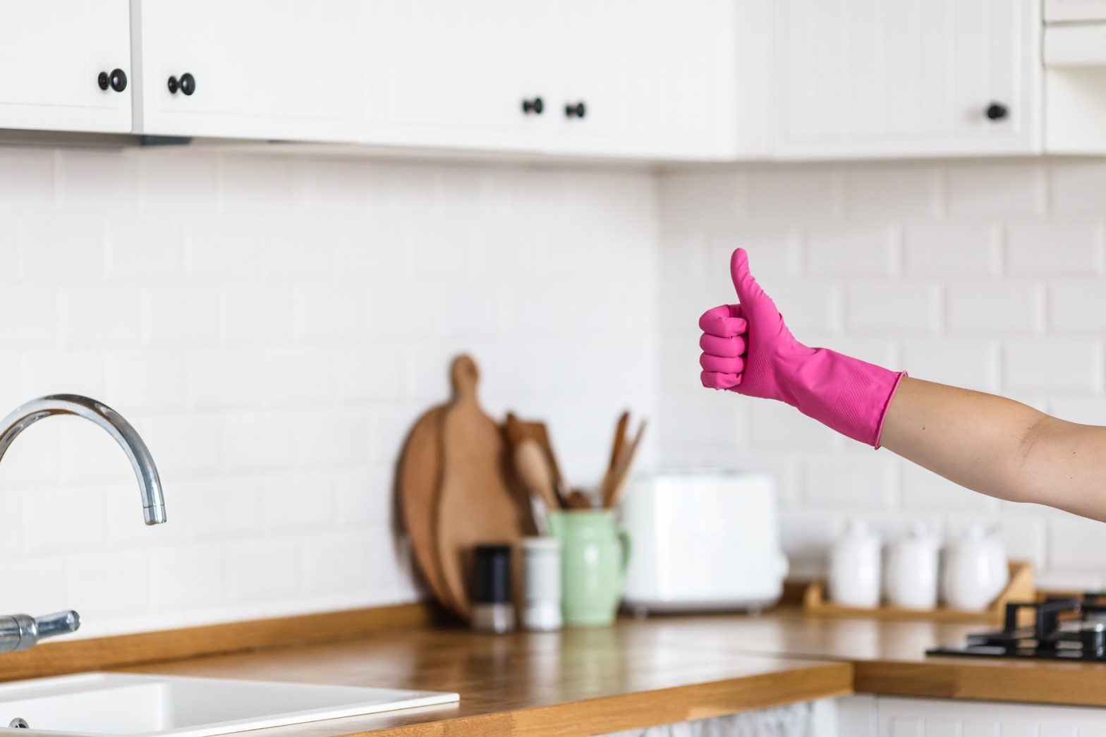 Clean kitchen backsplash tiles with hand showing thumbs up
